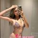 Attractive woman in a colorful bikini, taking a selfie in a bathroom. Premium escort services.