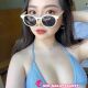 Attractive young woman wearing sunglasses and a blue bikini top. KL call girl.