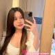 Young woman in white, taking a selfie. Malaysia escort service.