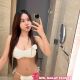 Woman in white lingerie taking a selfie in a bathroom.